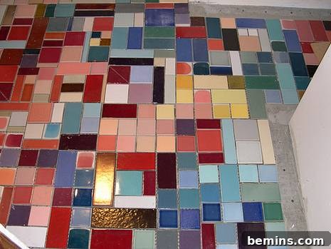 A bathroom floor with a variety of colored and sized tile pieces laid out before grouting.