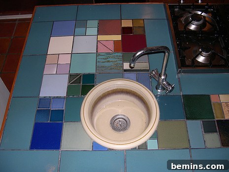 A kitchen countertop designed with colorful tiles near the stove and sink.