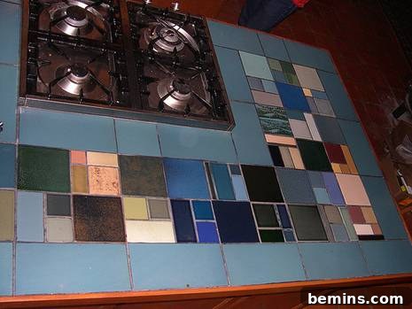 A close-up of the kitchen countertop near a gas stove, showcasing the colorful tile design.