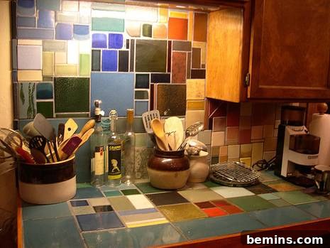 The multicolored tile kitchen counter and backsplash with containers of kitchen utensils on it.