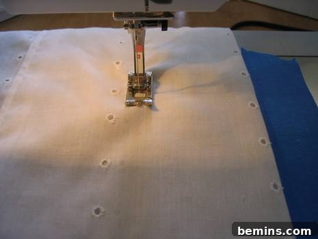 A white cloth is being sewed with a small machine.