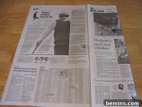 A newspaper being folded in preparation for creating an origami baseball mitt.