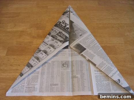 The newspaper origami craft, showing a second iteration of folding the corners towards the center.