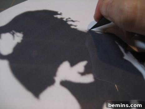 A close-up of a meticulously hand-cut stencil on acetate, demonstrating the precise craftsmanship required before its application to a t-shirt.