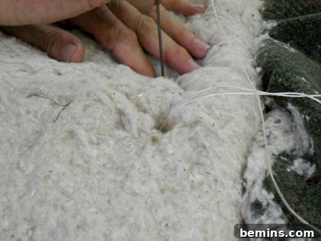 Close-up of the tufting needle emerging from the top layer, ready for the intricate tuft formation