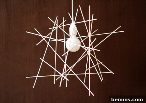 Handmade twig light fixture with white sticks arranged around a bulb, casting interesting shadows.