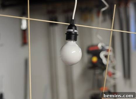 Attaching the first dowel rod to the lamp cord using epoxy glue.