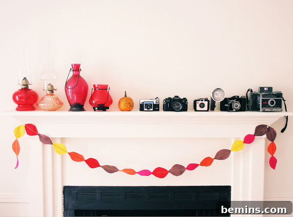 7 Fall Garlands to Craft for a Cozy Weekend 2 DIY felt leaf garland in autumn colors hanging against a white wall, featuring red, orange, and yellow leaves.