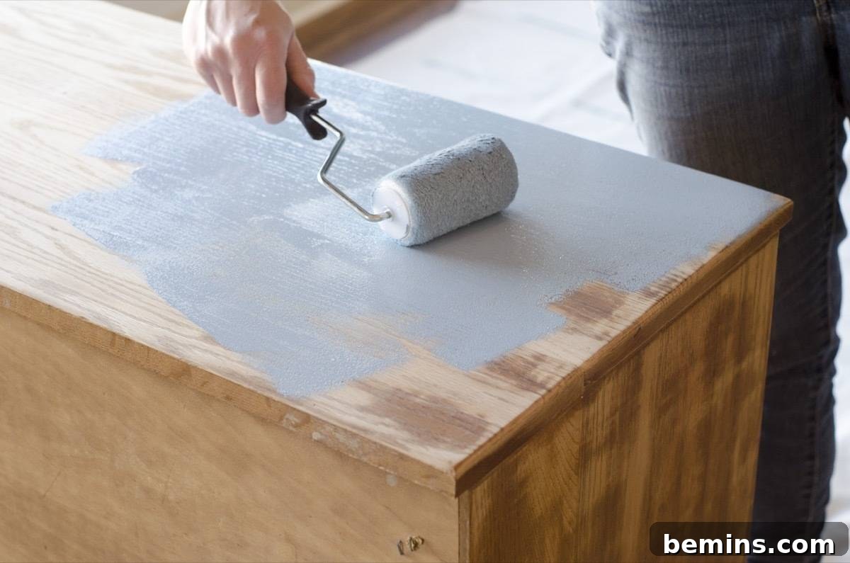 Image showing the painting process. A foam roller is being used to apply paint to the large, flat surfaces of the dresser.