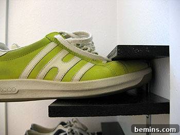 A close-up of a green shoe resting on a DIY shoe rack.