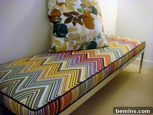 Rainbow colored chevrons decorate the fabric on a bench with a colorful floral pillow on top.