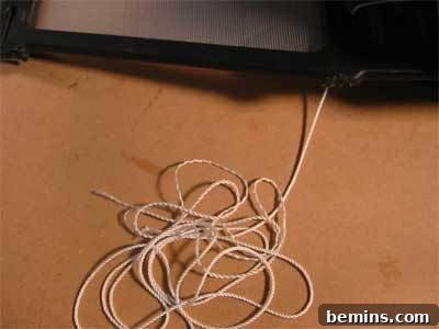 A white string is hanging from something black.