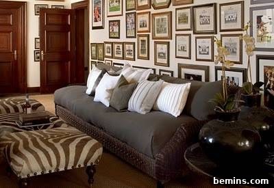 Gallery wall behind a gray cushion, showcasing a blend of artwork and personal photos.