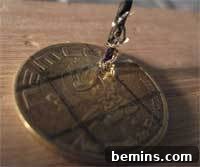 Drilling a hole in a coin using a drill press, demonstrating the precision required for this step.