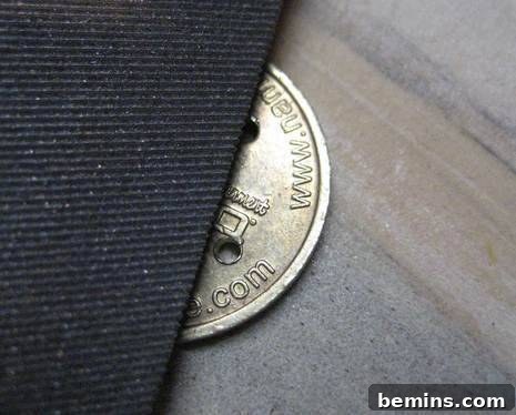 Filing the edges of a coin button, ensuring a smooth and safe surface for sewing onto fabric.