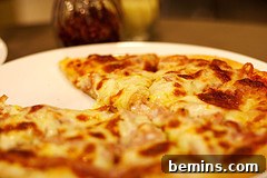 A white plate holds an entire pizza with one piece missing.
