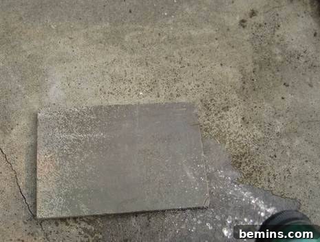 A grey plate is sitting on the concrete.