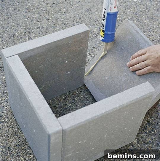 A person setting up four cement blocks together outside, demonstrating the construction of a DIY concrete planter