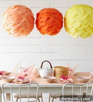 Colorful paper lanterns hanging above a dining table, creating a festive outdoor ambiance.
