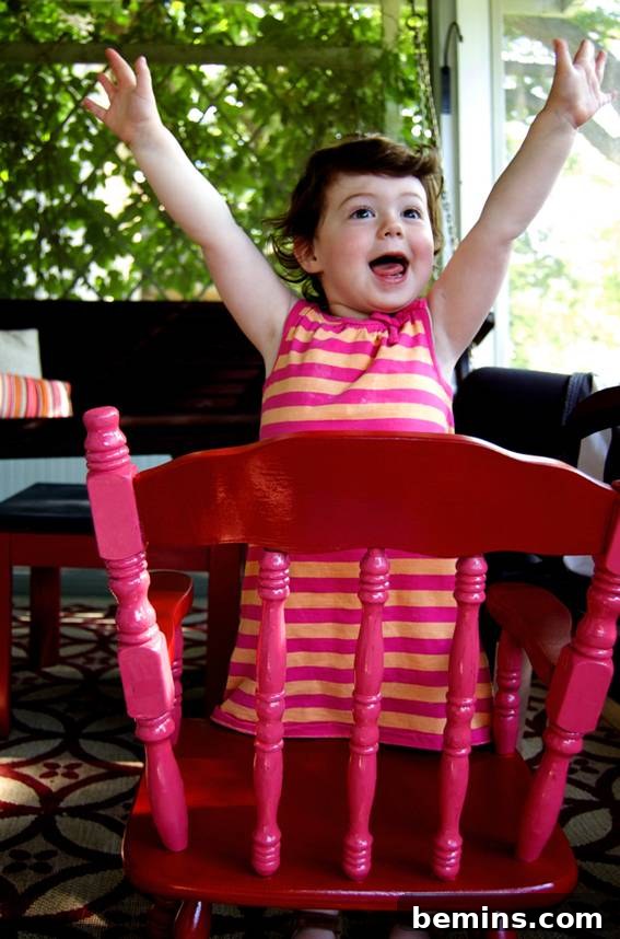 Ayla happily seated in her newly painted pink and red rocking chair on the porch, showing her enjoyment