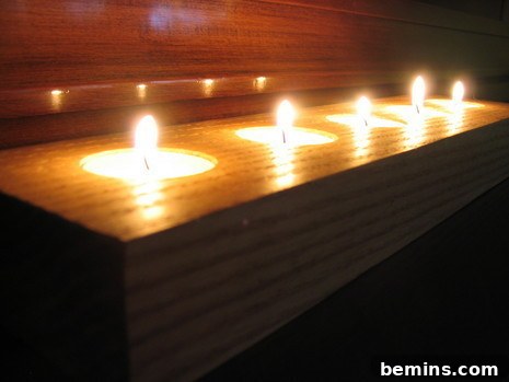 Group of tea candles in wooden holder.