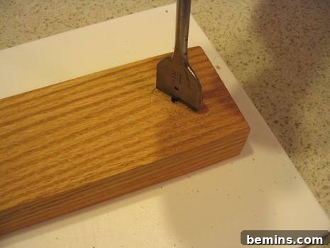 A wooden block has a tool stuck in it.