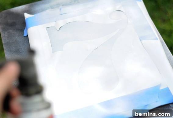 DIY Graphic Art on a Budget: Quick & Easy Projects 7 Applying the second color of spray paint to the canvas with the stencil in place