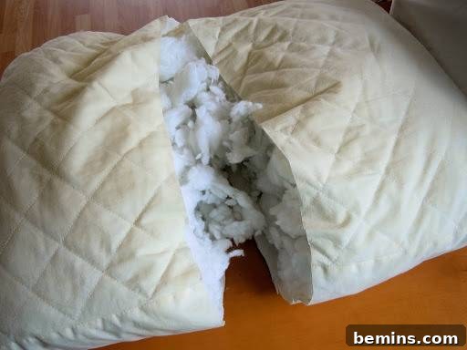 Turning Old Pillows into Dreamy Comfort: A DIY Transformation 6 Image illustrating the process of cutting a bed pillow in half to create smaller pillow forms for throw pillows.