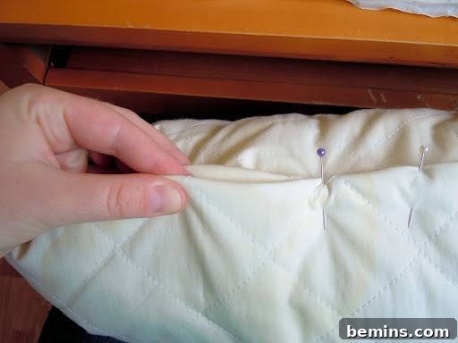 Turning Old Pillows into Dreamy Comfort: A DIY Transformation 9 Hands using straight pins to secure the folded edges of a pillow before sewing.