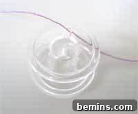 Sewing Machine Basics: A Guy's (and Gal's) Guide to Stitches & Seams Crafting Confidence: Mastering Stitches and Seams for Everyone 3 A close-up of a transparent plastic bobbin with thread wound around it