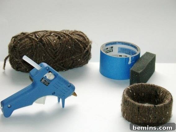 Materials needed for the DIY yarn bracelet: empty painter's tape roll, yarn, foam, and hot glue gun