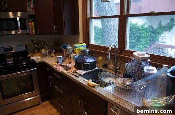 A severely disorganized kitchen cupboard with items spilling out.