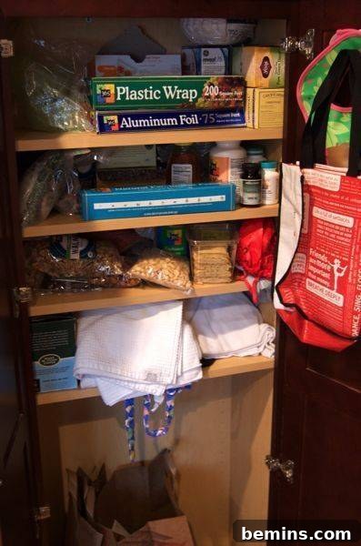 A crowded and disorganized pantry shelf with various food items haphazardly arranged.
