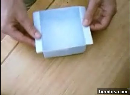 A person is folding a paper and making it into a paper bowl.