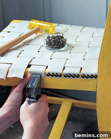 Ingenious Seating Solution 3 Close-up of a person attaching webbing to a chair frame with a staple gun.