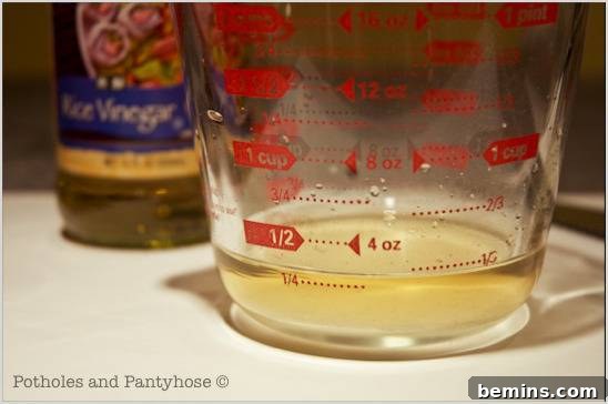 The measuring cup and vinegar bottle is on the table.