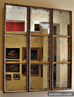 A window that shows several framed paintings outside of it.
