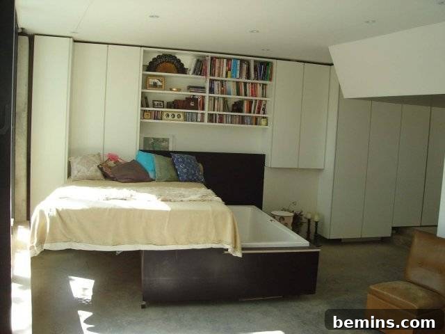 A bed set up in a room with books on the wall.