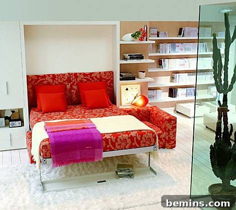A pull down bed made in a red and gold cover with red pillows and a tan throw with a tall cactus behind green glass.