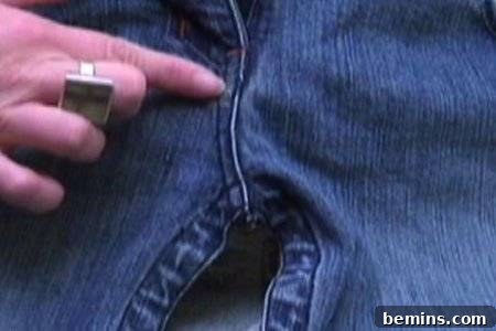 From Denim to Dream Skirt: A DIY Transformation 10 A woman pointing to the crotch area of a pair of blue jeans, highlighting the area to focus on.