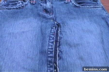 From Denim to Dream Skirt: A DIY Transformation 14 Faded pair of blue jeans with the pant legs sewn together to make a skirt, showing the pinned front seam.