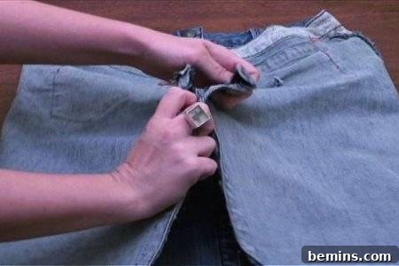 From Denim to Dream Skirt: A DIY Transformation 16 Ringed fingers opening a zip in the jeans pant, showing the back seam preparation.