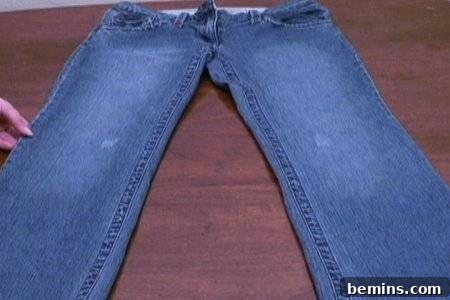 From Denim to Dream Skirt: A DIY Transformation 3 Slim style faded jeans laid out on a wooden table, ready for transformation.