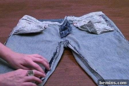 From Denim to Dream Skirt: A DIY Transformation 8 "Altering the old jeans into Skirt" by ripping the seams.">
<p style="text-align: center;"><em>Preparing the Jeans Panels</em></p>
<h3>Step 3: Preparing the Front and Back Seams</h3>
<p>Now that the side seams are removed, rip the front seam up to where the zipper begins and the back seam up to where your belt loops start. This will allow you to flatten the jeans and create the basic skirt shape.</p>
<img src="https://bemins.com/wp-content/uploads/2025/11/img_579_8.jpg" alt="A beautiful hand is showing a jeans pant spreading on the floor, illustrating the separated fabric panels.">
<img src="https://bemins.com/wp-content/uploads/2025/11/img_579_9.jpg" alt=