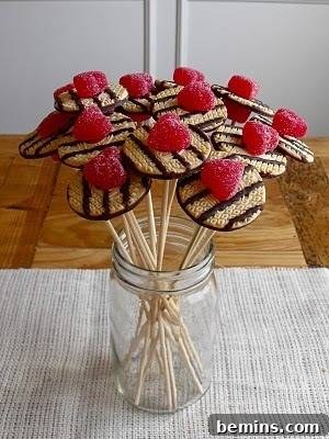 DIY Edible Masterpieces: Arrangements and Centerpieces 6 Fudge round cookies with a candied fruit on top stuck on straws in a mason jar.