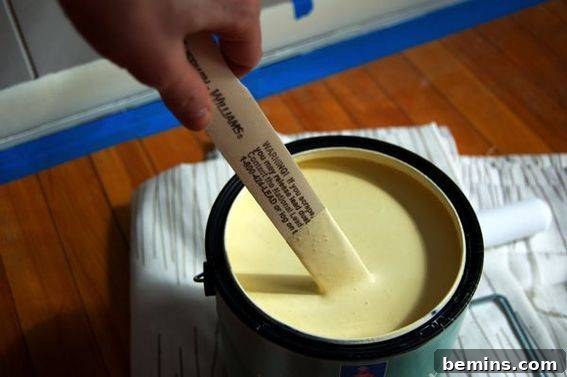 Sherwin Williams Friendly Yellow - Applying yellow paint for the initial stripe design on the nursery walls.