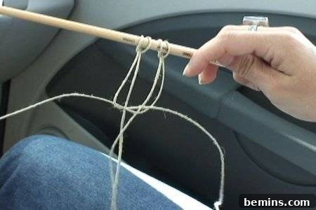 Hand holding a stick with hanging hemp twine in a car