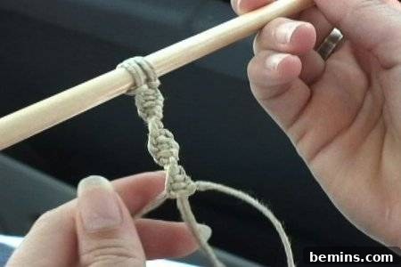 Hands holding a stick with hanging hemp twine