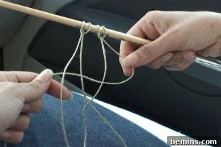 Hands holding a stick with hanging hemp twine