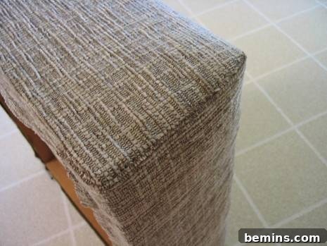 Ottoman with open bottom covered in beige woven fabric showcasing upholstery techniques